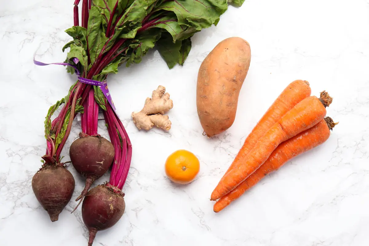 display of beets, carrots, a sweet potato, ginger and an orange