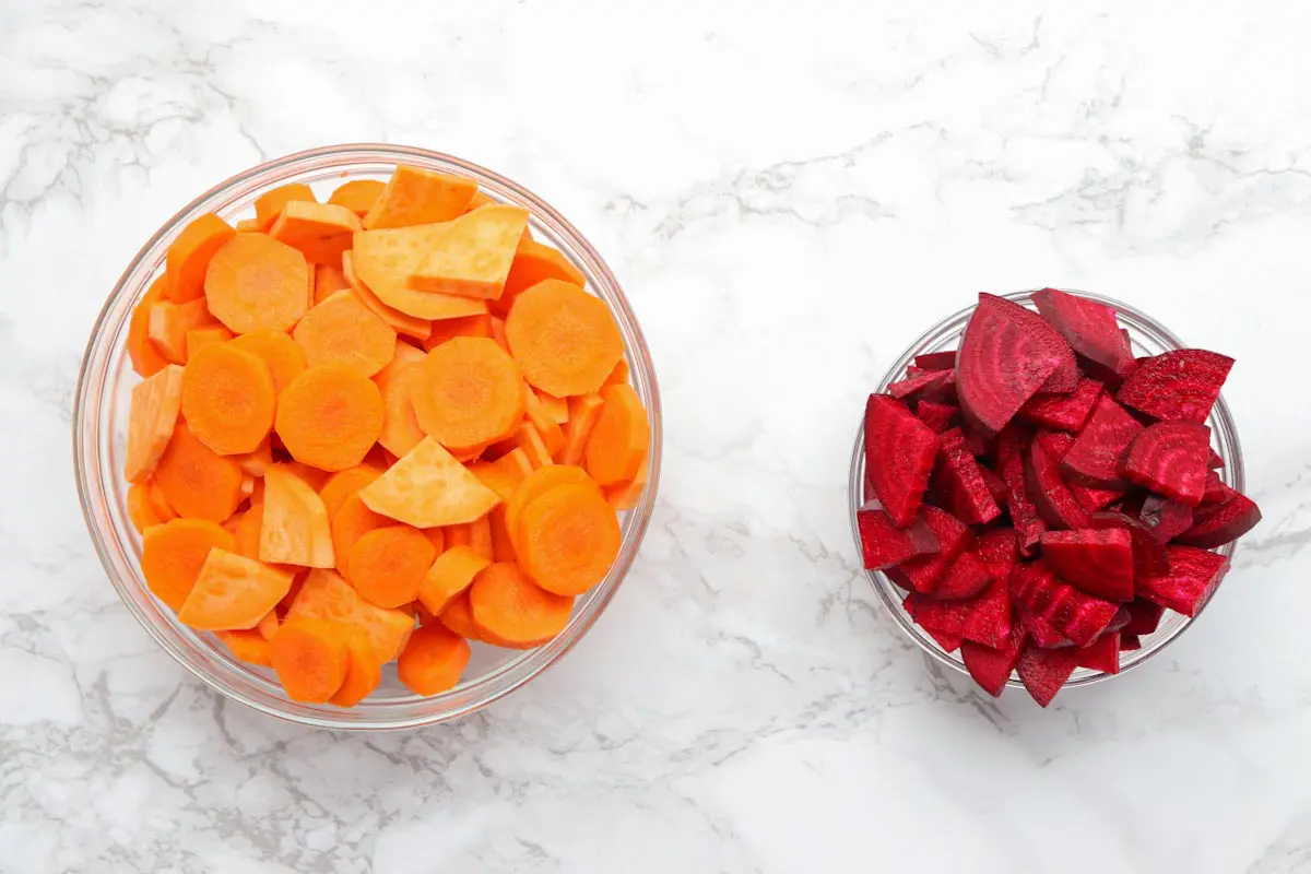 chopped carrots and sweet potatoes in a bowl and chopped beets in a separate bowl