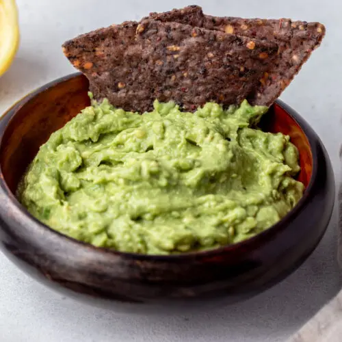 juiced lemon sitting next to a bowl of simple guacamole