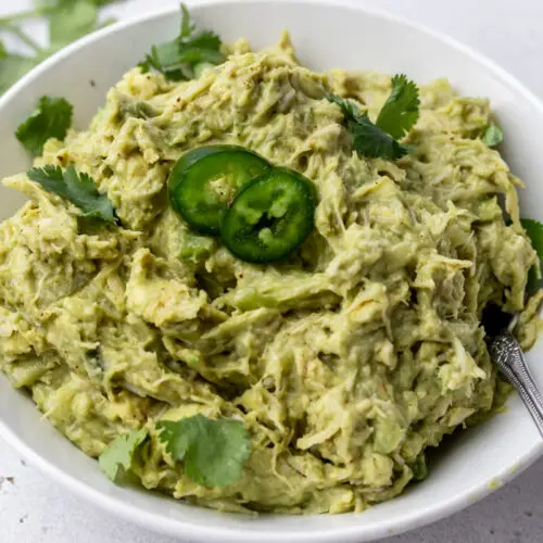 spoon in a bowl of guacamole chicken salad