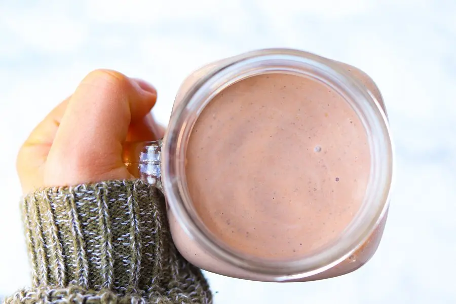 handheld mug of rich chocolate smoothie with chia seeds