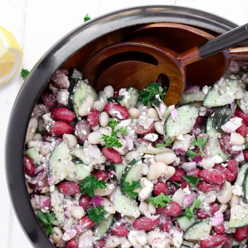 Kidney and cannellini beans mixed with feta, cucumbers and onions in a large salad bowl