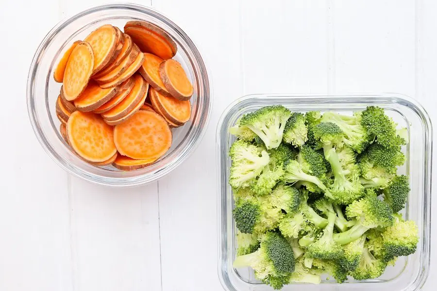 two glass containers of sliced raw sweet potatoes and chopped raw broccoli