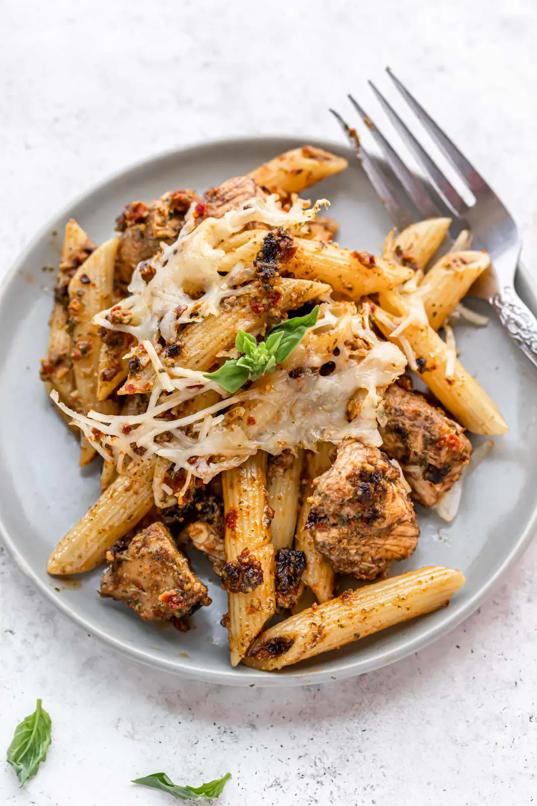 plated chicken and pasta dish with basil leaves