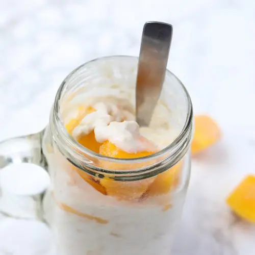 overnight oats in a glass mag topped with frozen chunks of mango