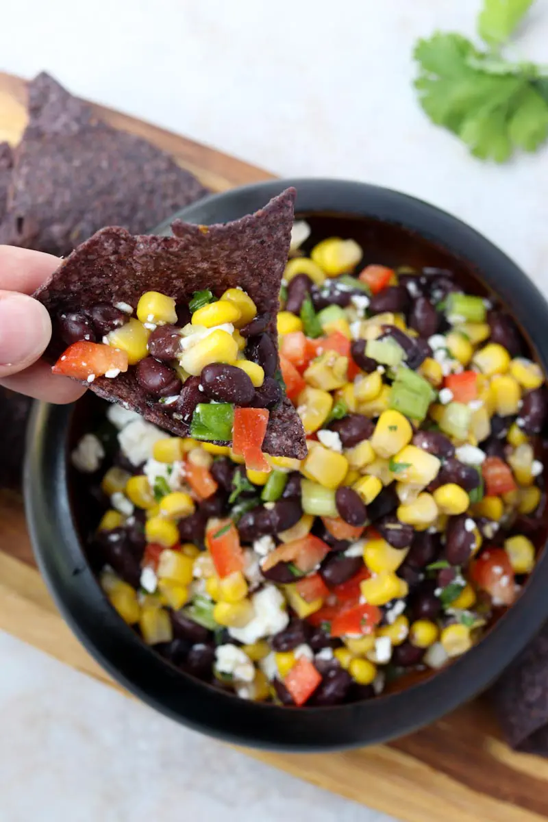 black tortilla chip topped with black bean and corn salsa