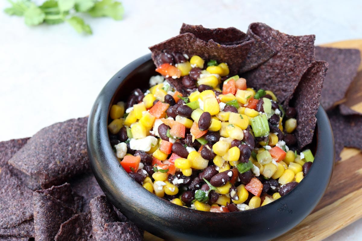 black tortilla chips sitting in a bowl of black bean and corn salad