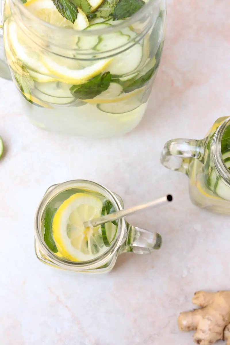 overhead shot of two glass mugs of water with lemon slices and mint