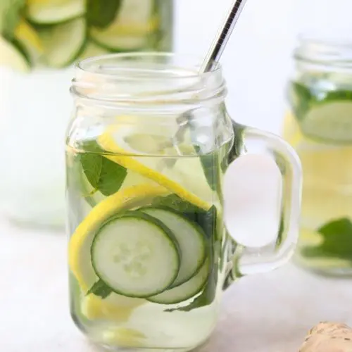 close up of single glass mug of cucumbers, lemon, mint and ginger in water