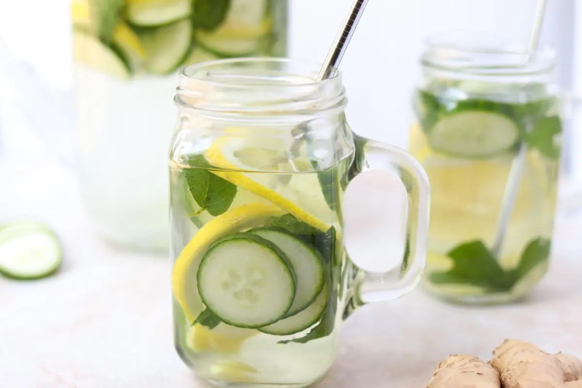 close up of a glass mug of cucumbers, lemon, mint and ginger in water