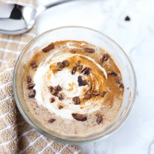 glass container of pudding with yogurt and cinnamon swirled on top