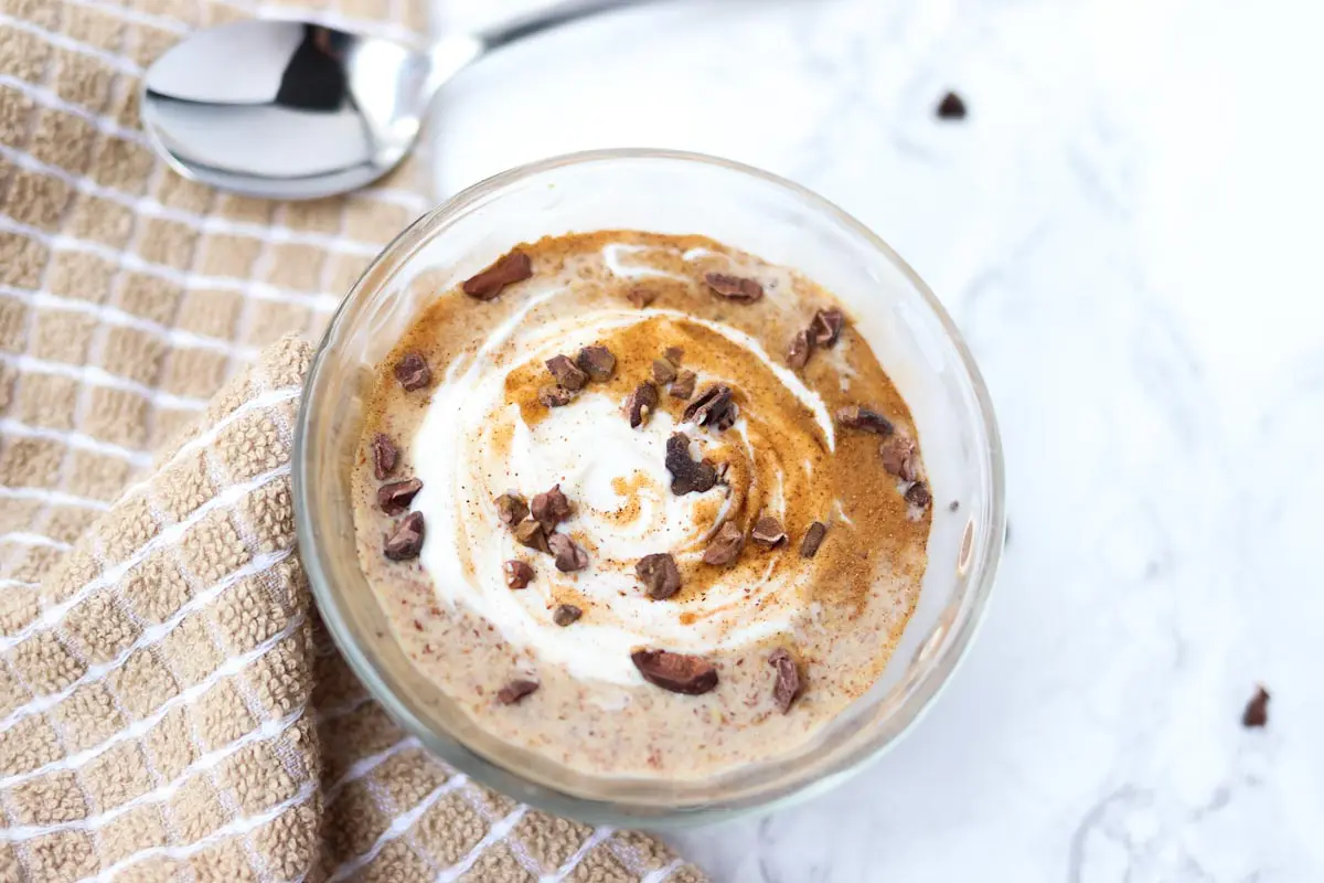 glass container of pudding with yogurt and cinnamon swirled on top