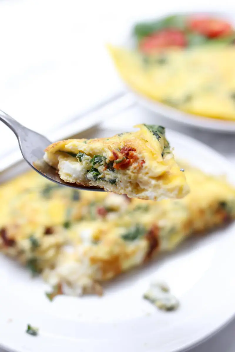 close up of fork holding a bite of omelette