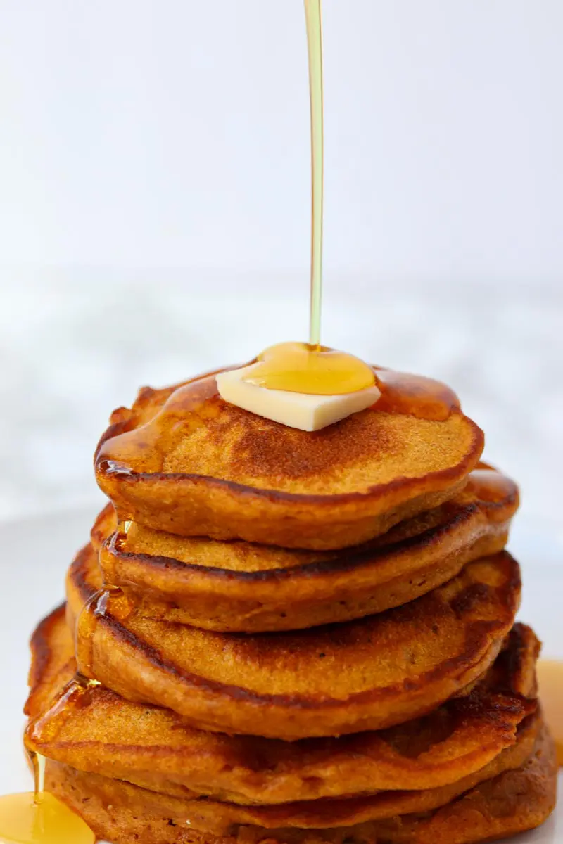 single stream of syrup poured over a pancake stack with butter