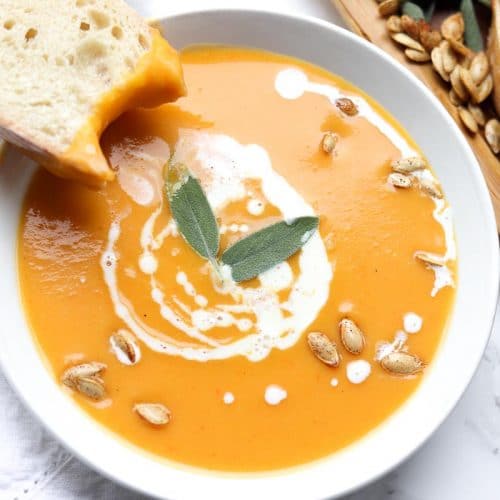 butternut squash soup topped with coconut cream, seeds and sage leaves