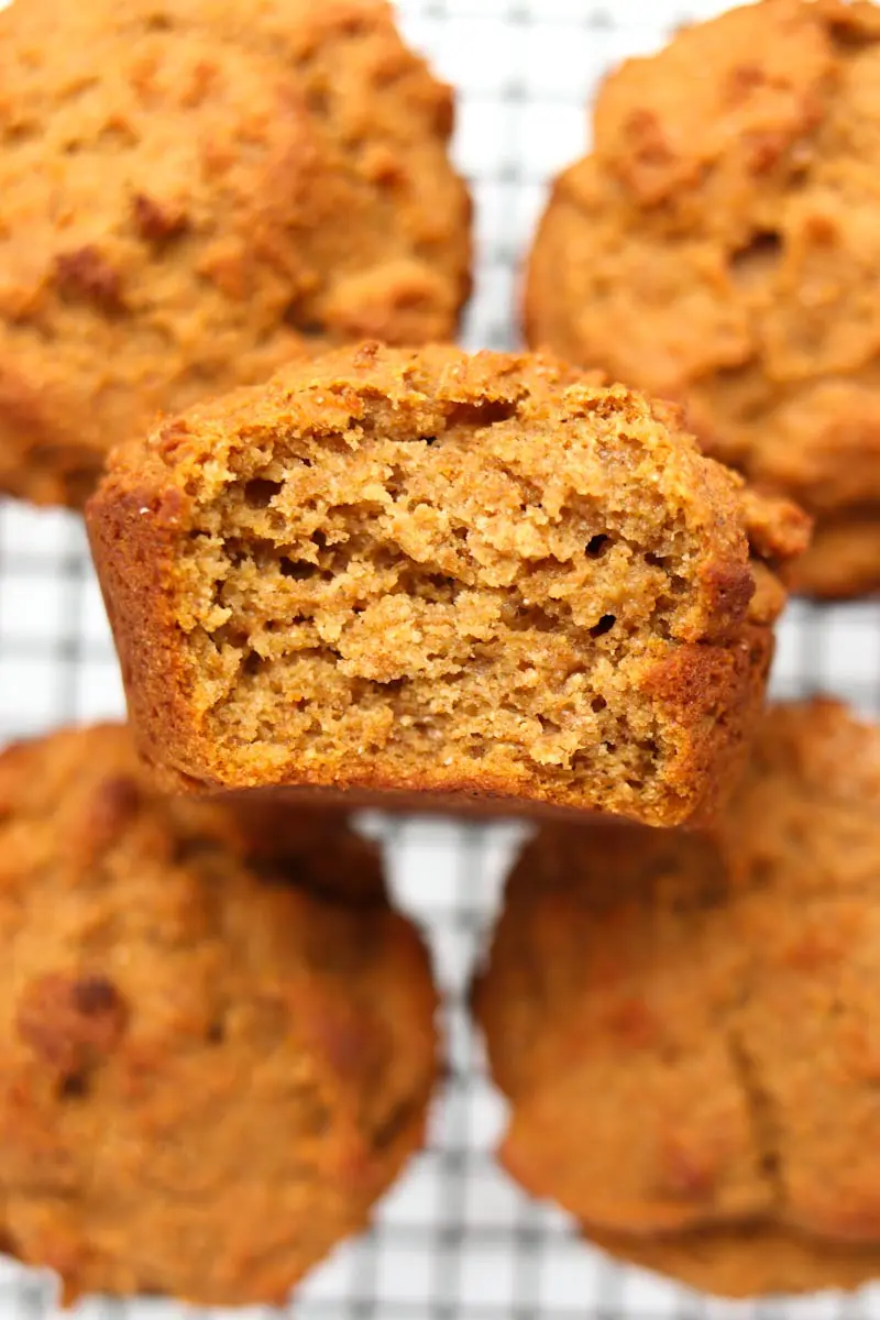 bite taken out of a muffin resting face up on top of other muffins