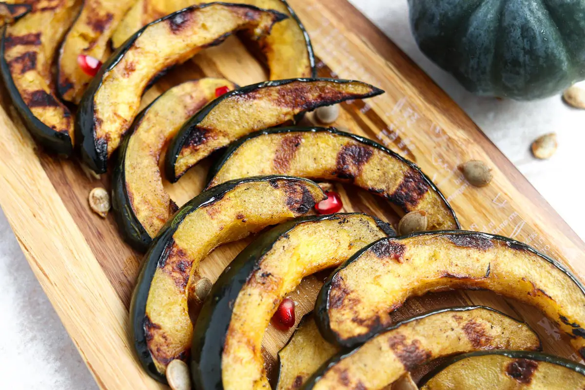 acorn squash slices with grill marks laying on a platter topped with roasted acorn seeds
