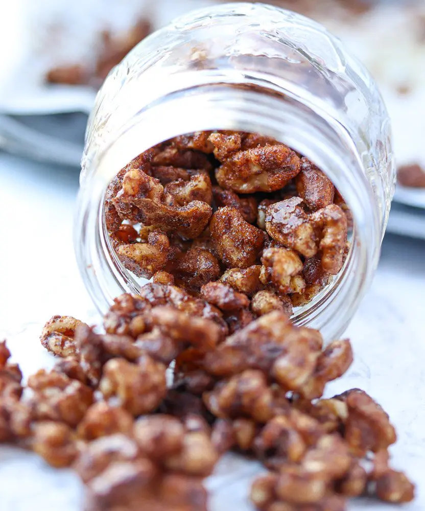 glass jar of walnuts roasted in spices spilling out of the jar