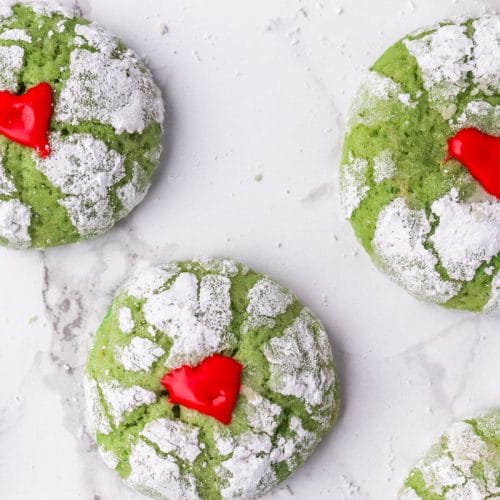 overhead shot of green cookies covered in powdered sugar and red hearts