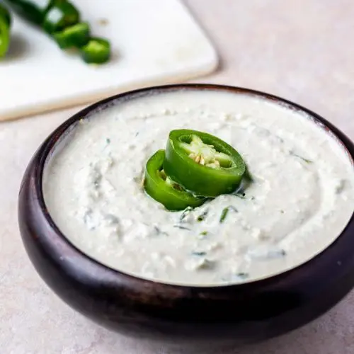 sliced jalapenos on a bowl of jalapeno artichoke dip