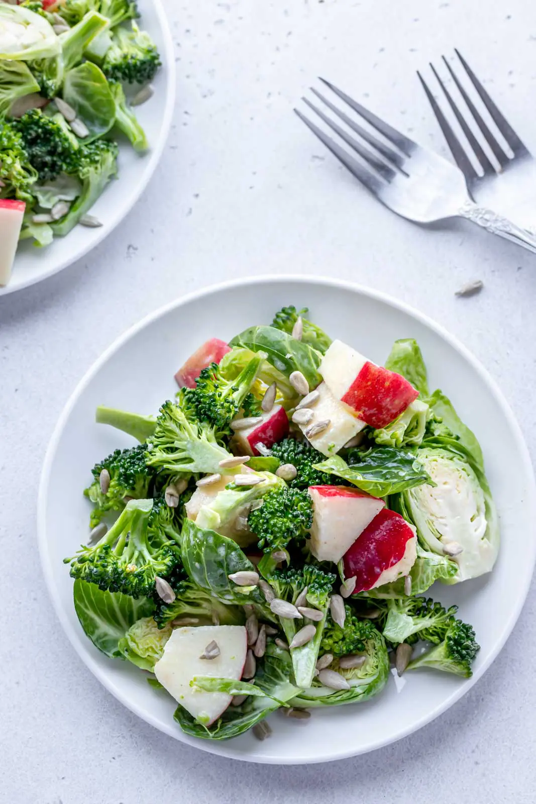 shaved brussels sprouts, broccoli and red apples on a plate