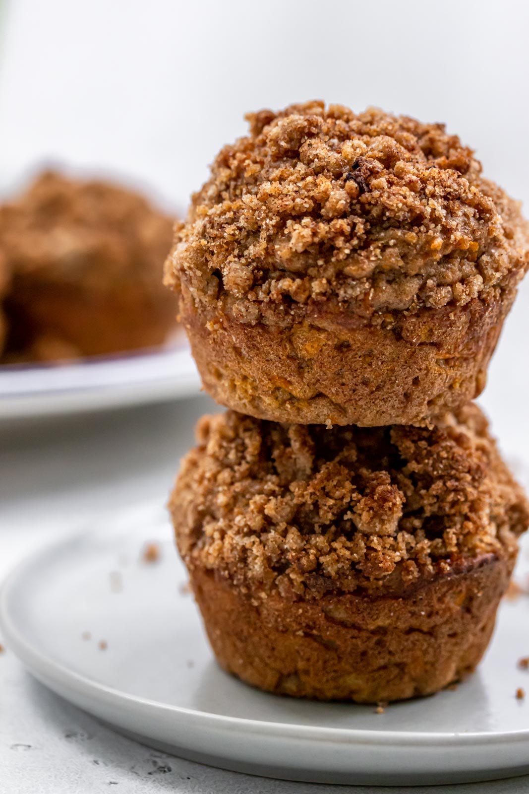 two muffins with cinnamon sugar crumble topping stacked