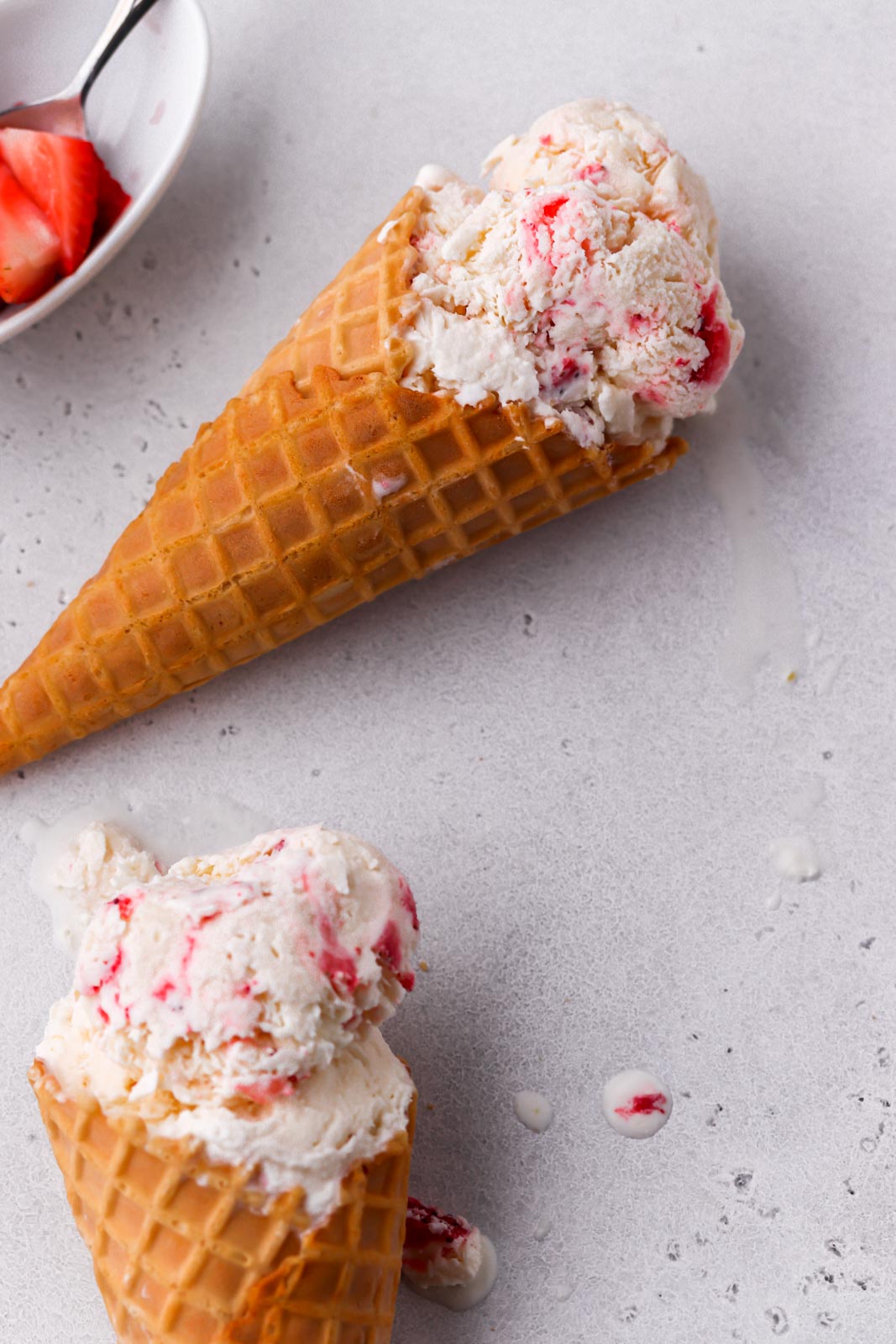 two ice cream cones with strawberries