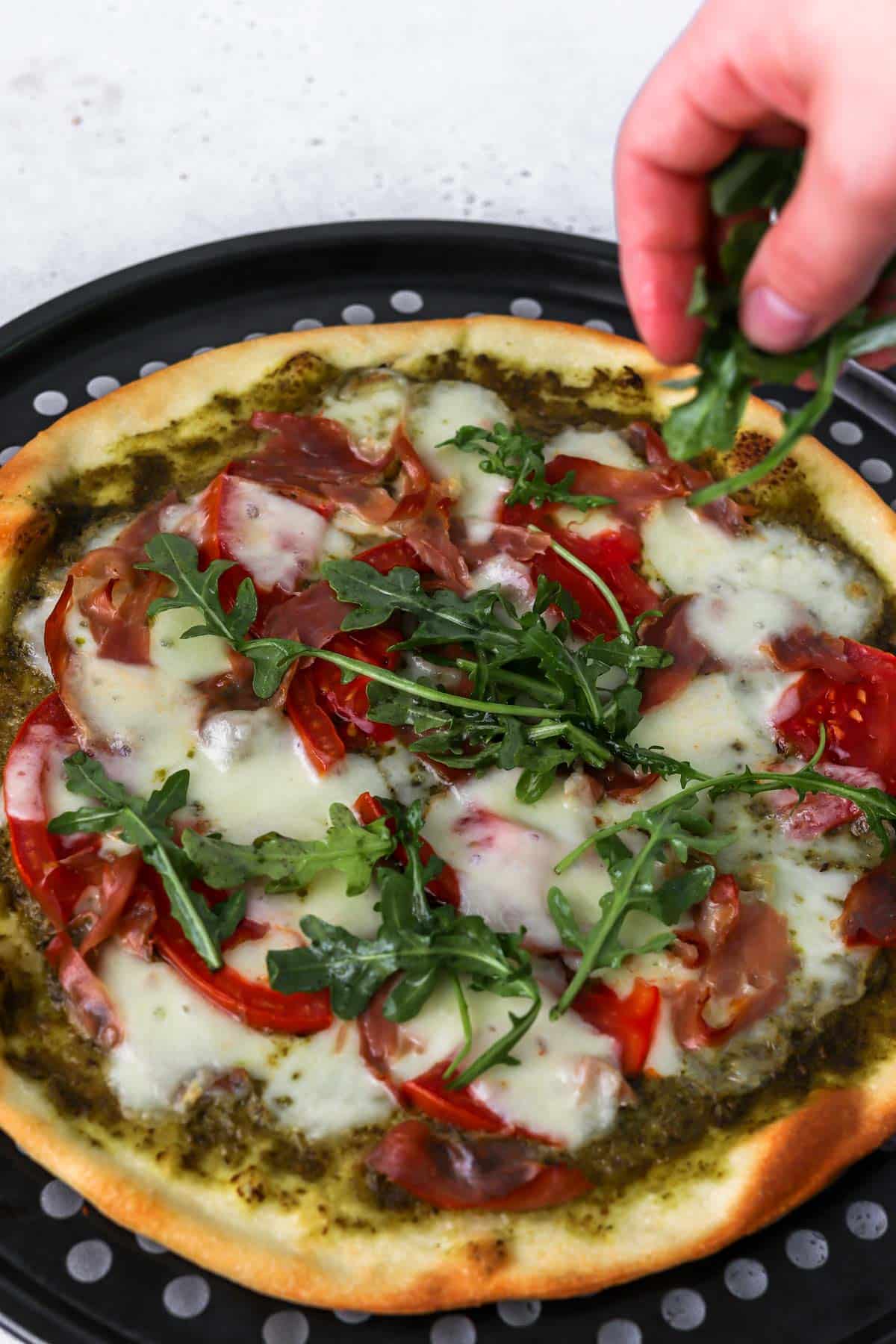 Arugula being added to pizza