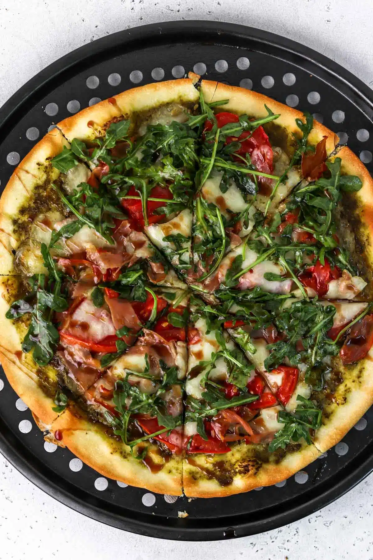 homemade pizza with arugula, tomato and prosciutto