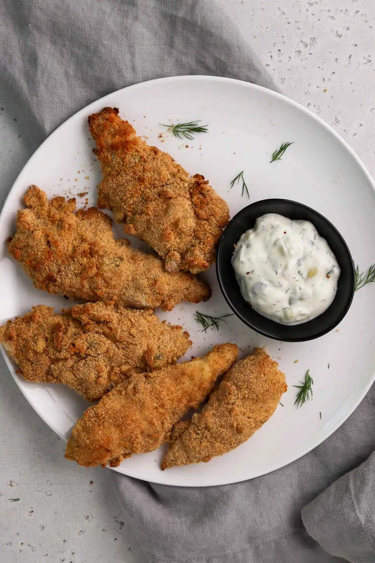 tzatziki chicken tenders on a plate surrounding homemade tzatziki