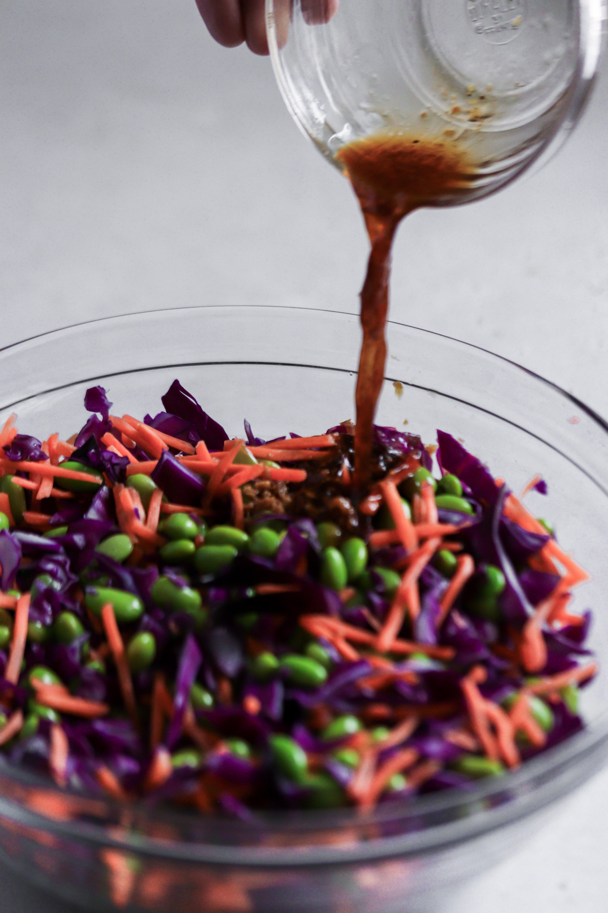 Pouring the soy-dressing into the edamame salad.