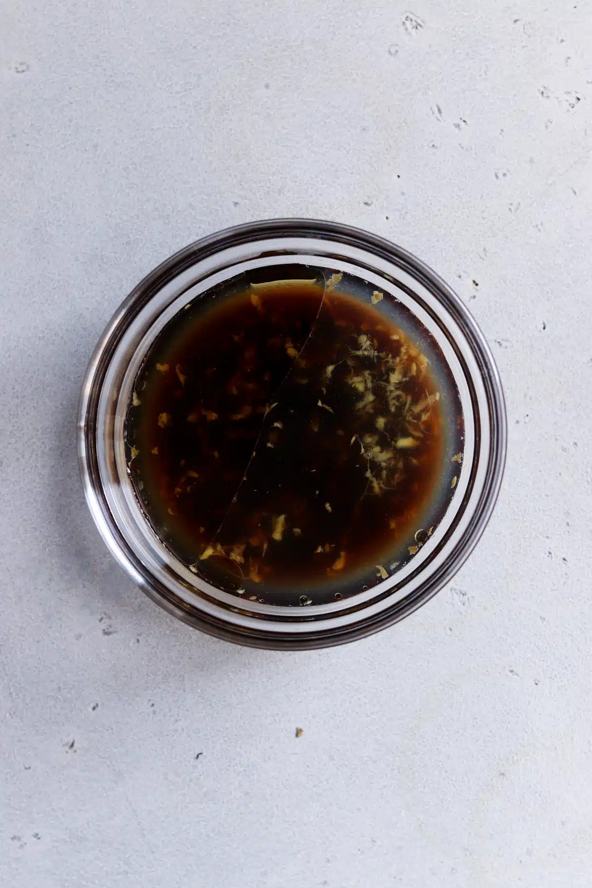 Small bowl of dressing with ginger, lime juice, soy sauce and seasoned rice vinegar.