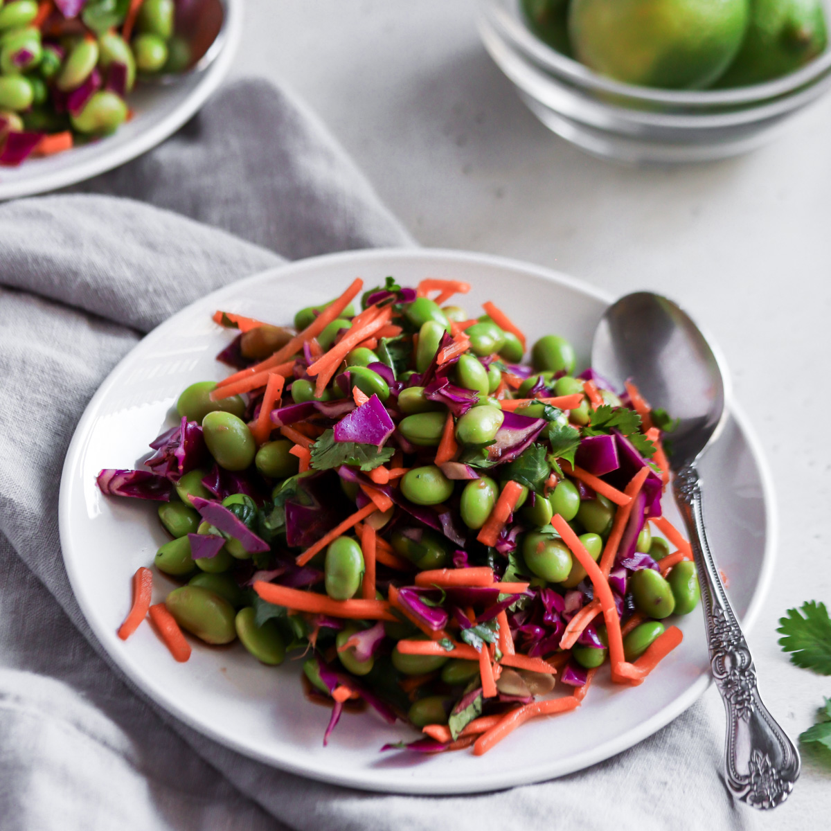 Edamame salad served on a white plate with spoon.